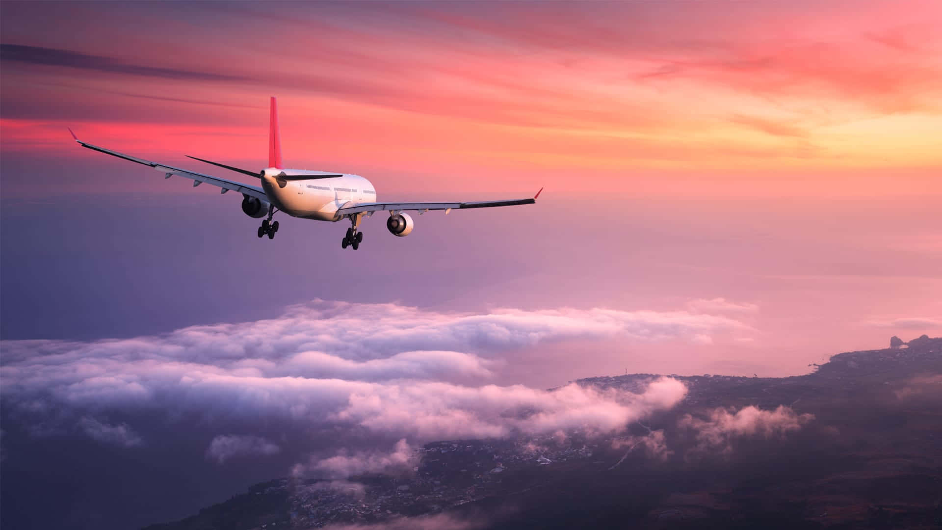 A pink passenger plane flying in the sky against a backdrop of clouds Wallpaper