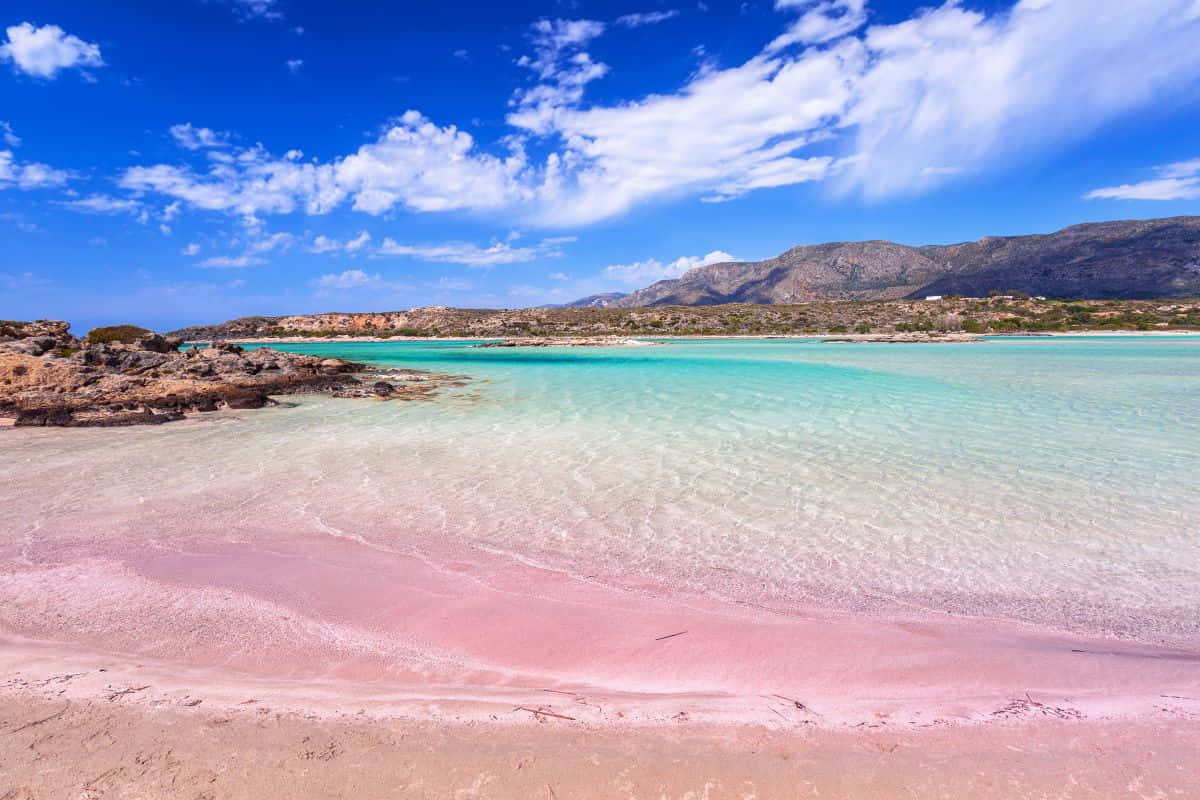 Unavista Fascinante De La Playa De Arena Rosa Bajo Un Vibrante Cielo Azul Fondo de pantalla