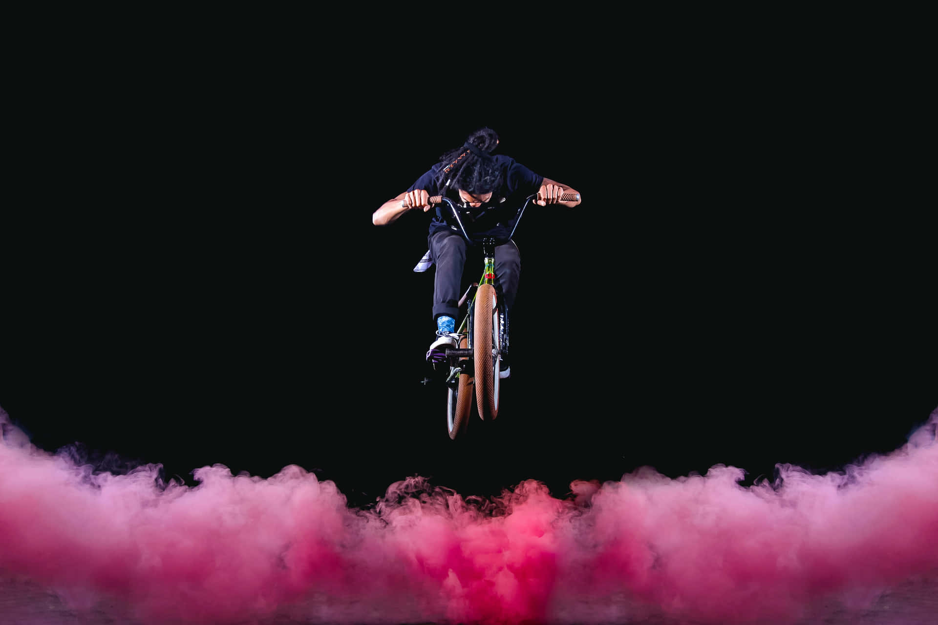A Person Riding A Bike Through Pink Smoke