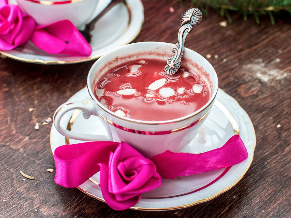 A tantalizing cup of Pink Tea served in an elegant teacup on a wooden table Wallpaper
