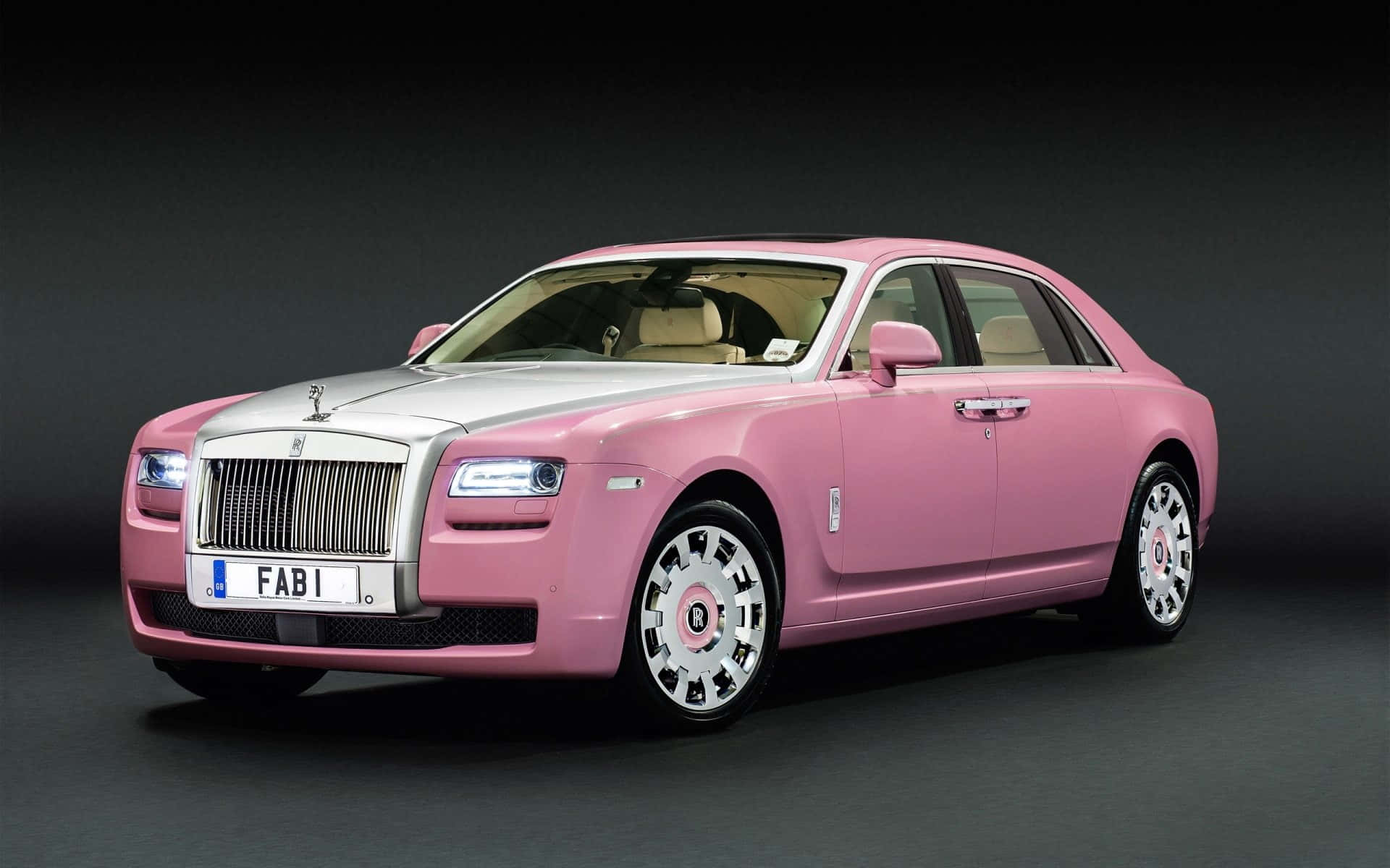 Et pink Rolls Royce vises i et mørkt rum Wallpaper
