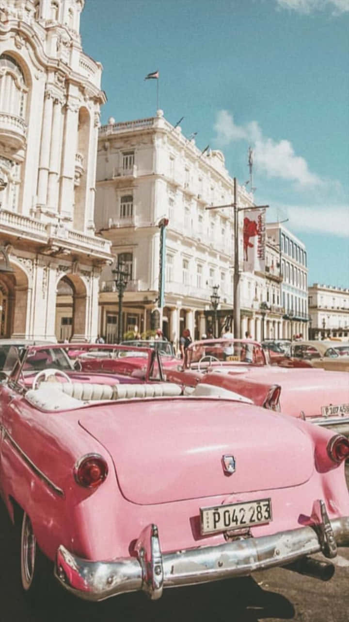 A Pink Car Parked In Front Of A Building Wallpaper