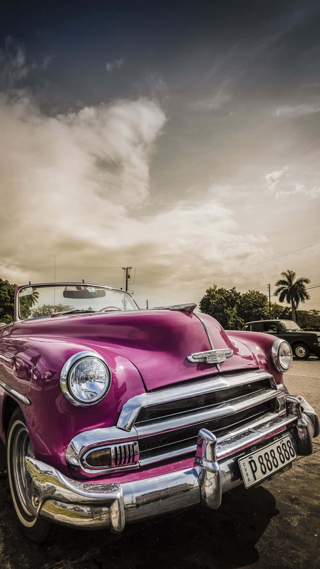 A Pink Vintage Car Parked In A Parking Lot Wallpaper