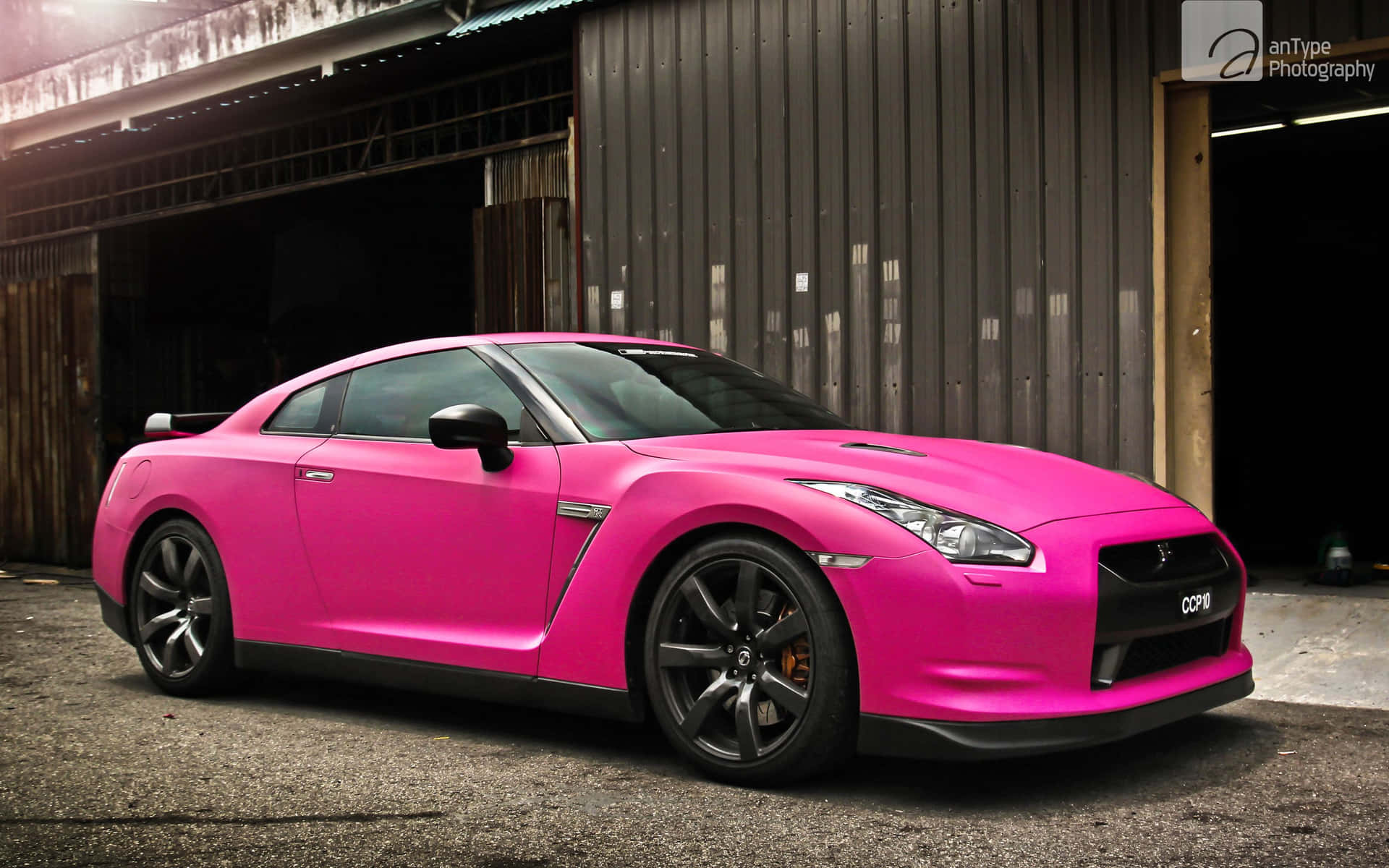 A Pink Nissan Gtr Parked In Front Of A Garage Wallpaper