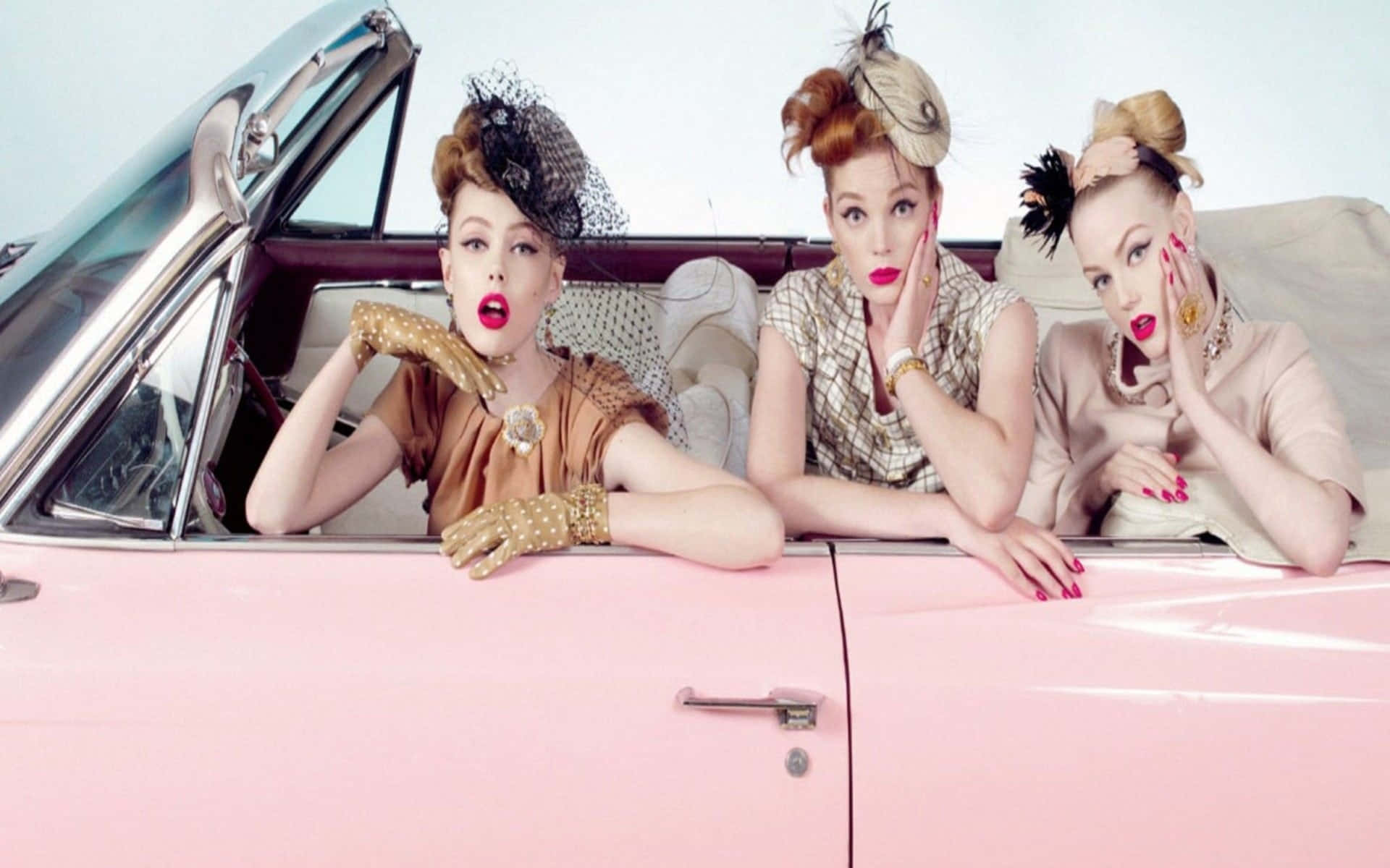 Tre kvinder siddende i en pink bil Wallpaper