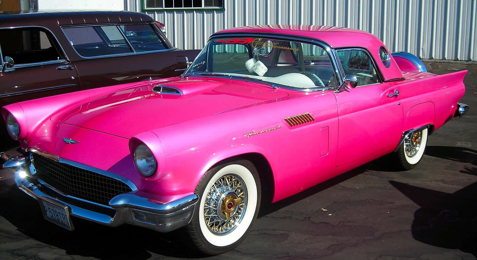 En smuk lyserød vintagebil parkeret i en solrig mark. Wallpaper