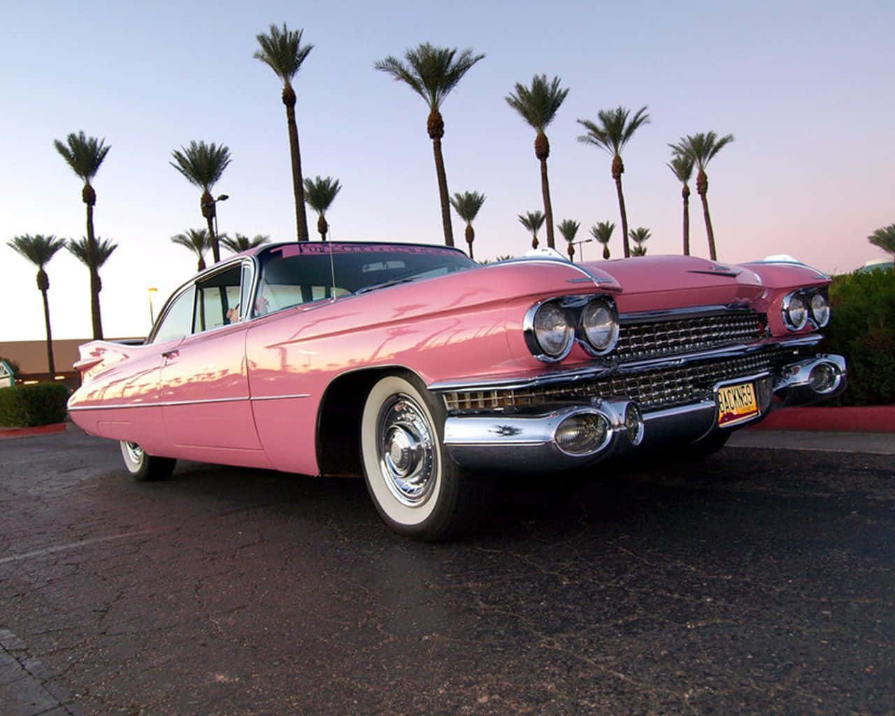 A timelessly elegant pink vintage car stands in the setting sun Wallpaper