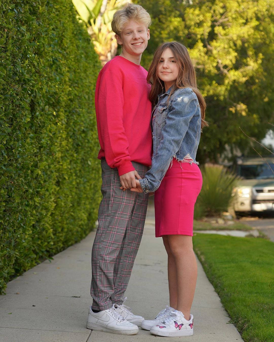 A Young Couple Standing On A Sidewalk Wallpaper