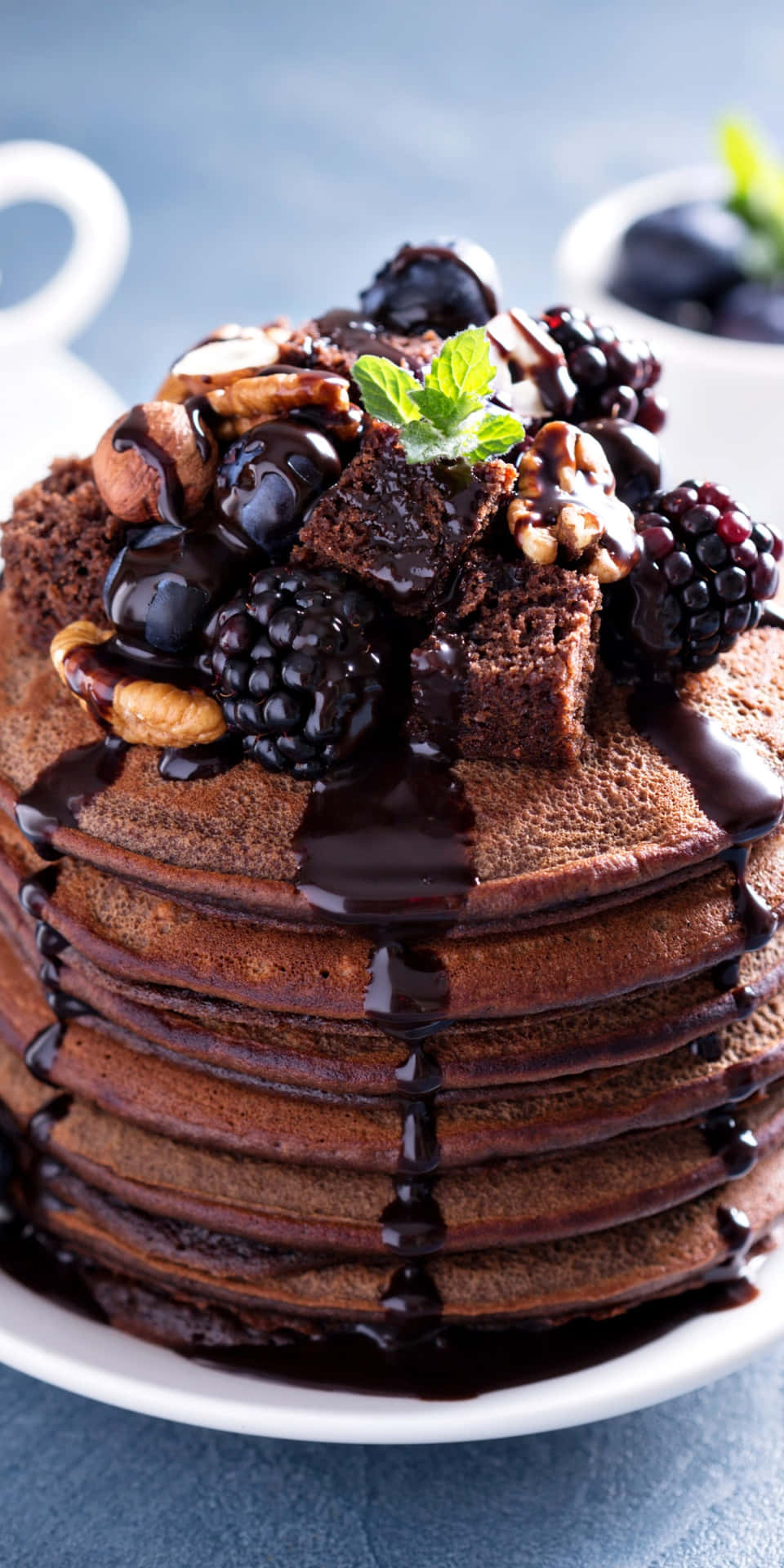 A Stack Of Chocolate Pancakes With Nuts And Syrup