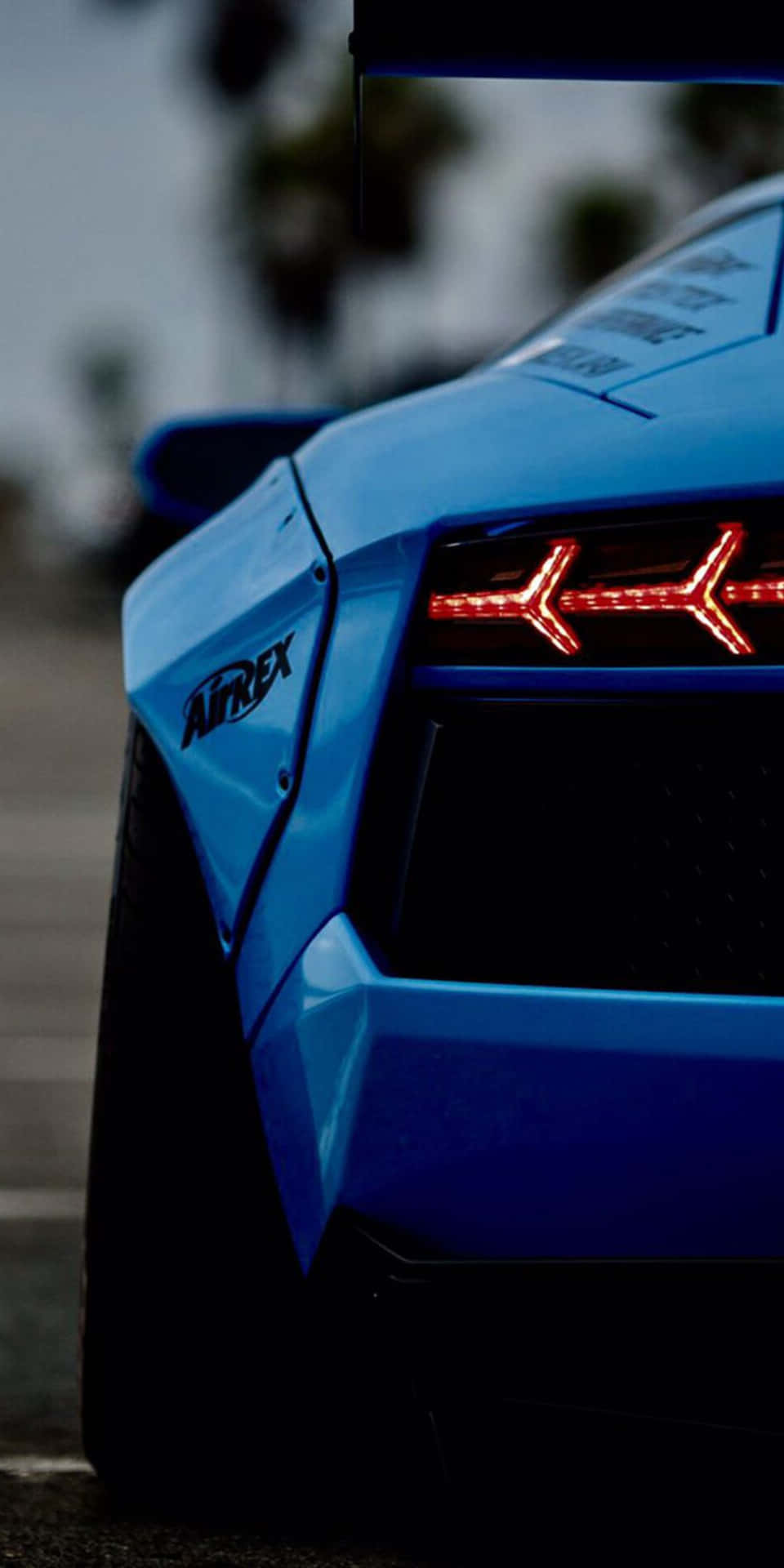 A Blue Sports Car With The Tail Lights On