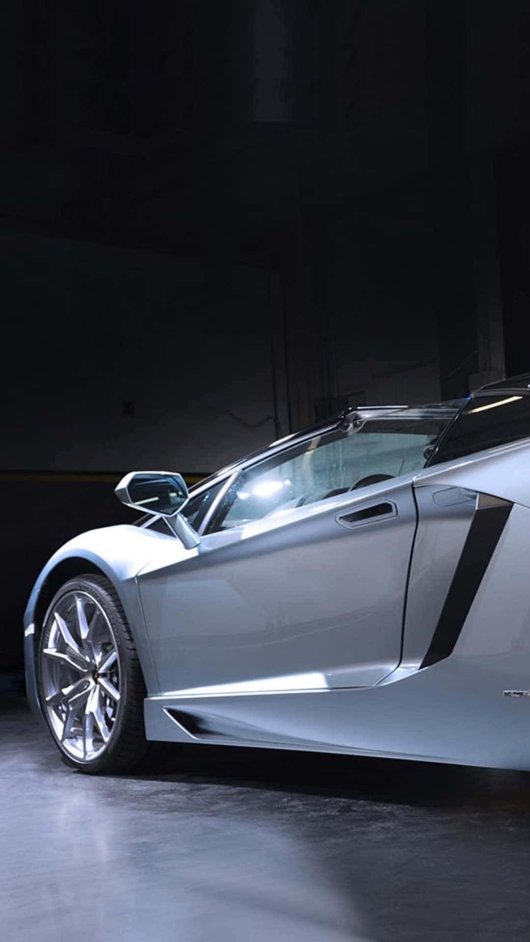 A Silver Sports Car Is Parked In A Dark Room