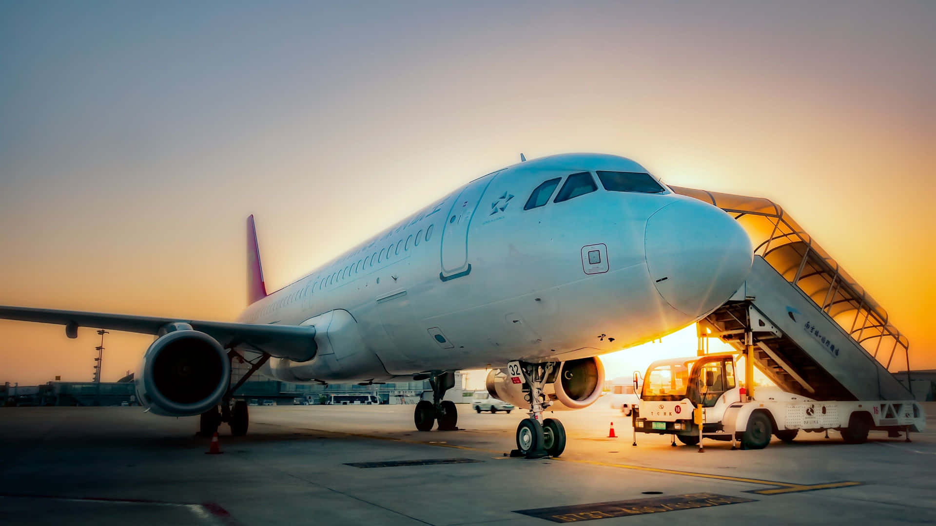 En passagerer fly er parkeret på et lufthavn. Wallpaper