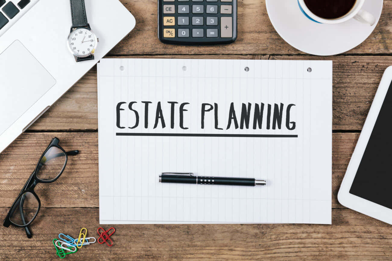 Estate Planning - A Note On A Desk With A Pen, Laptop, And Phone