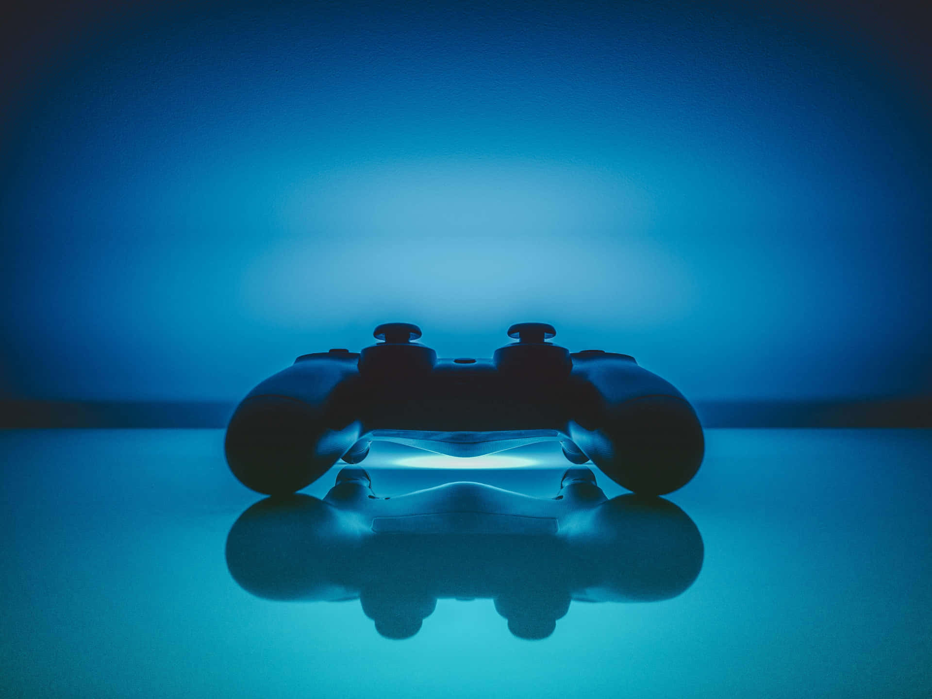 A Video Game Controller Is Sitting On A Blue Surface Wallpaper