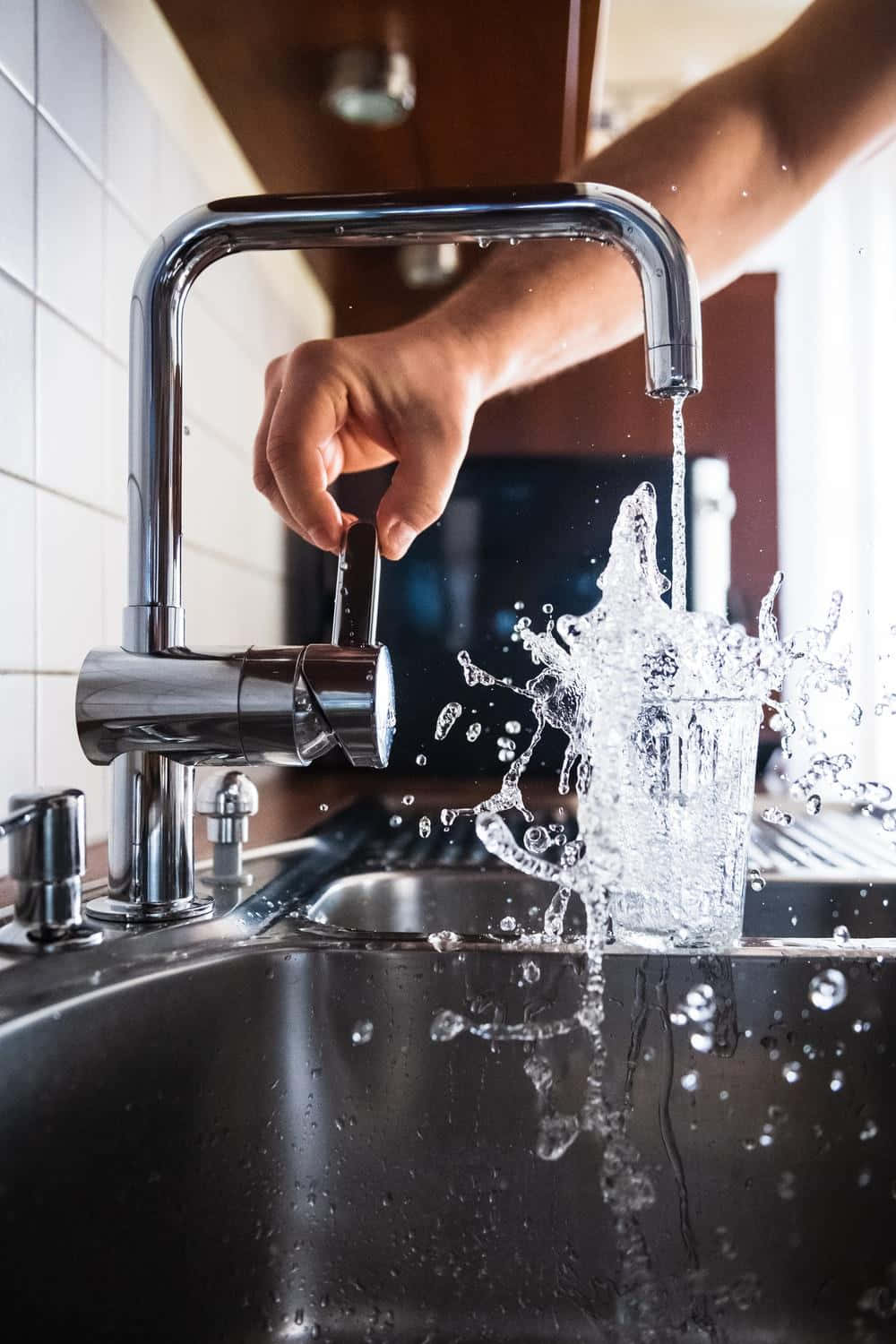 Eineperson Gießt Wasser In Ein Spülbecken In Der Küche.