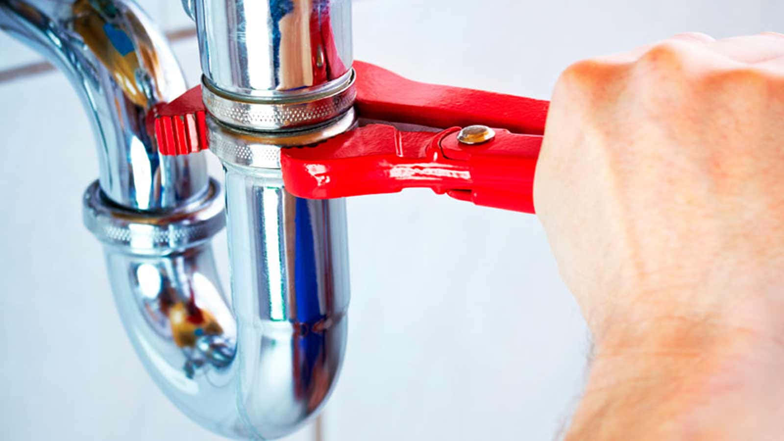 A Man Is Holding A Red Pliers To Fix A Faucet
