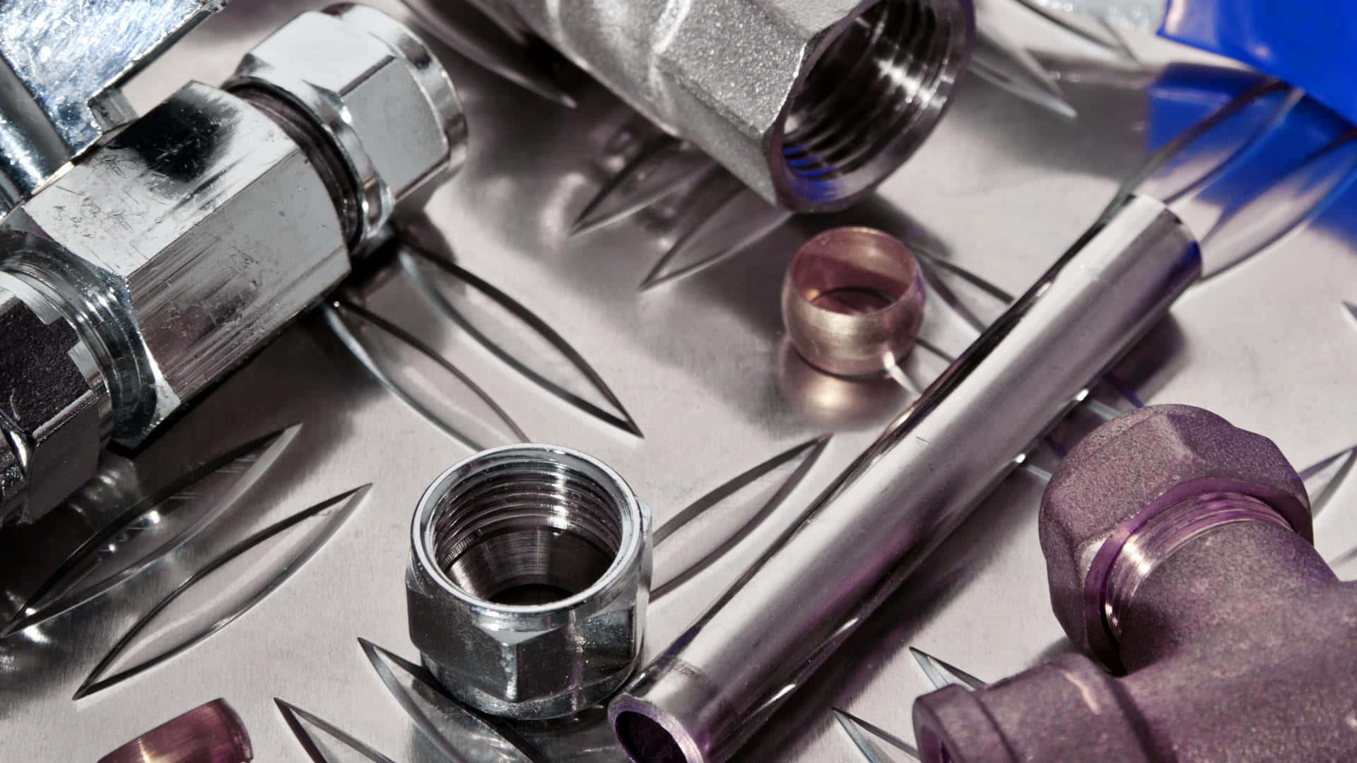 A Variety Of Metal Pipes And Fittings On A Metal Surface