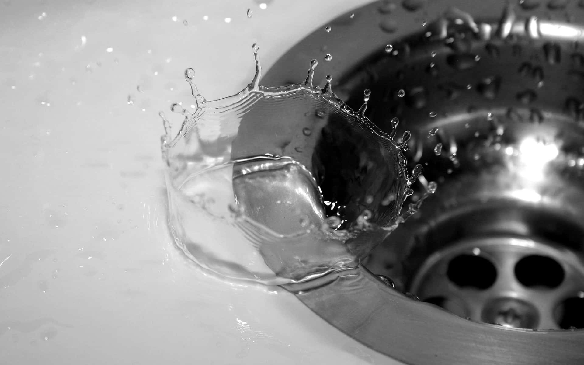 A Black And White Photo Of A Sink With Water Pouring Out