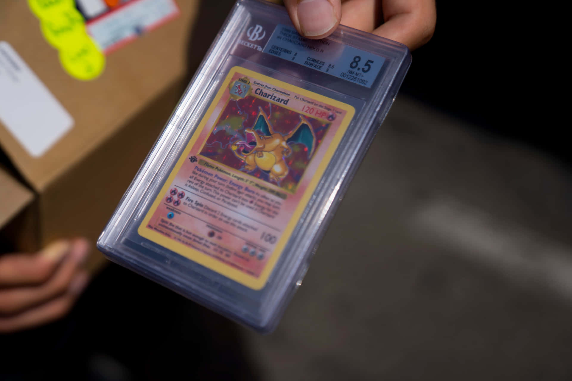 A Person Holding A Pokemon Card In A Box