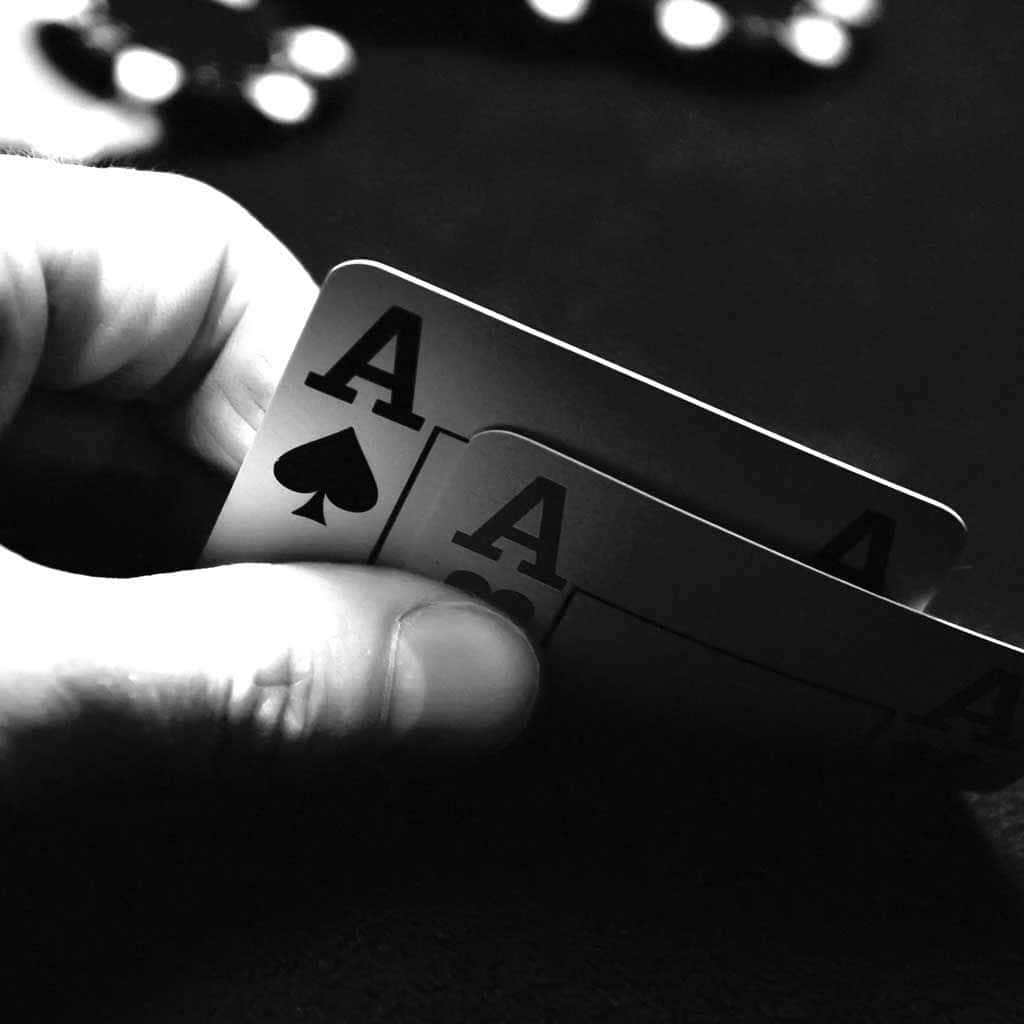A Hand Holding A Pair Of Aces On A Table
