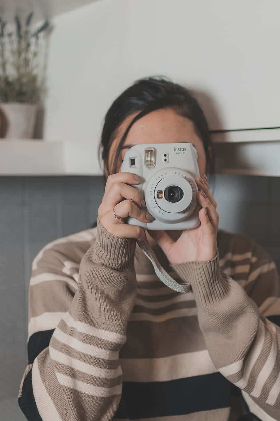 Kvinde med grå Instax Polaroid kamera billede mod hvid baggrund