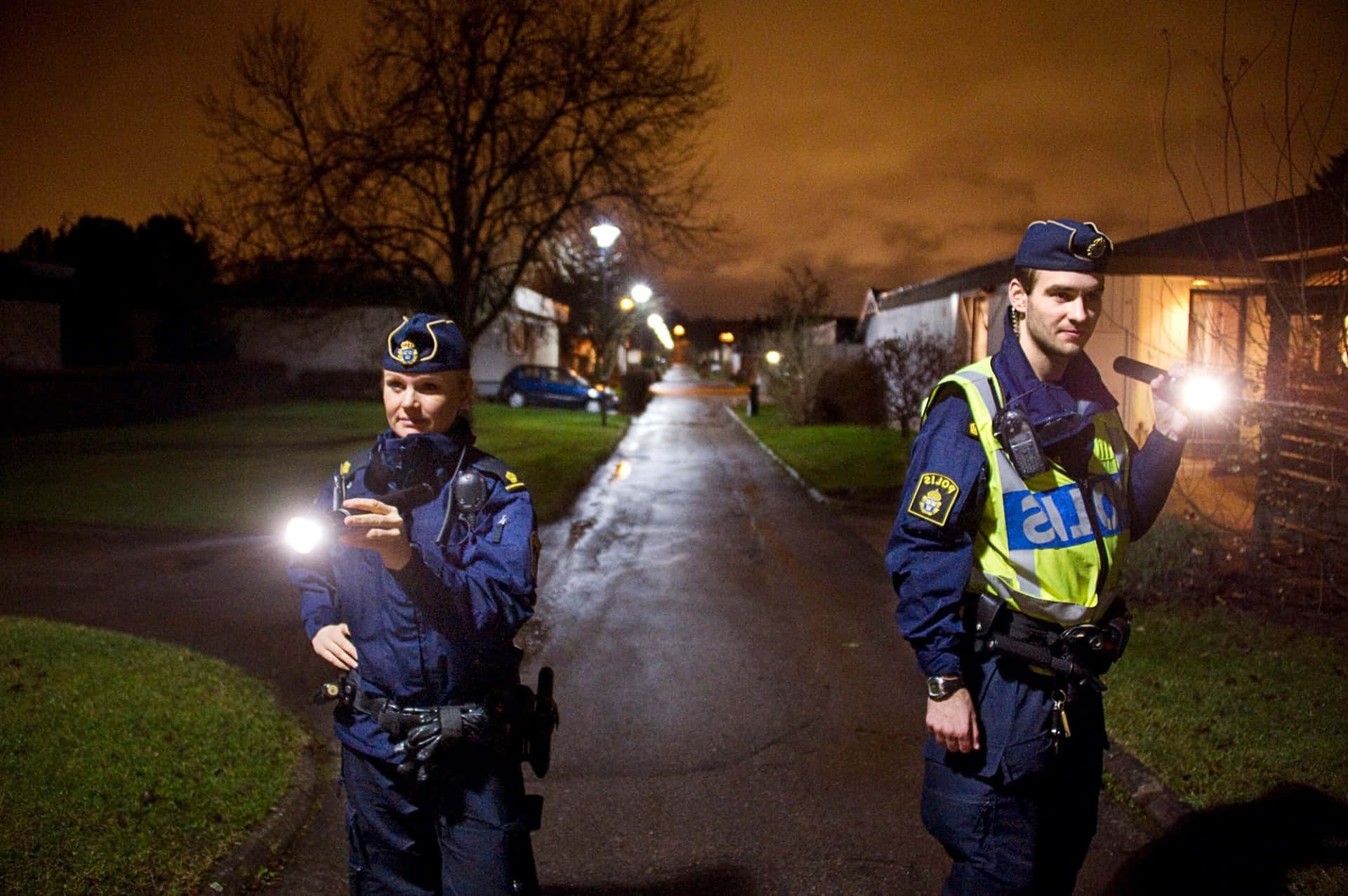 Two Police Officers Standing On A Street At Night