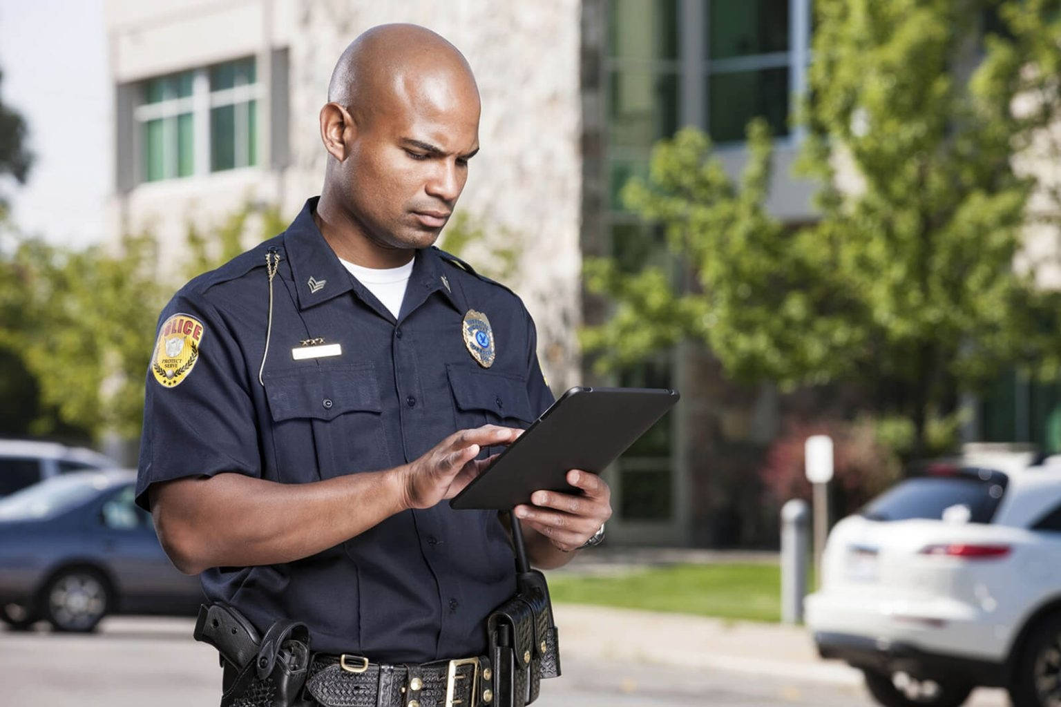 Police Officer Accessing Information on Handheld Device in the Field Wallpaper