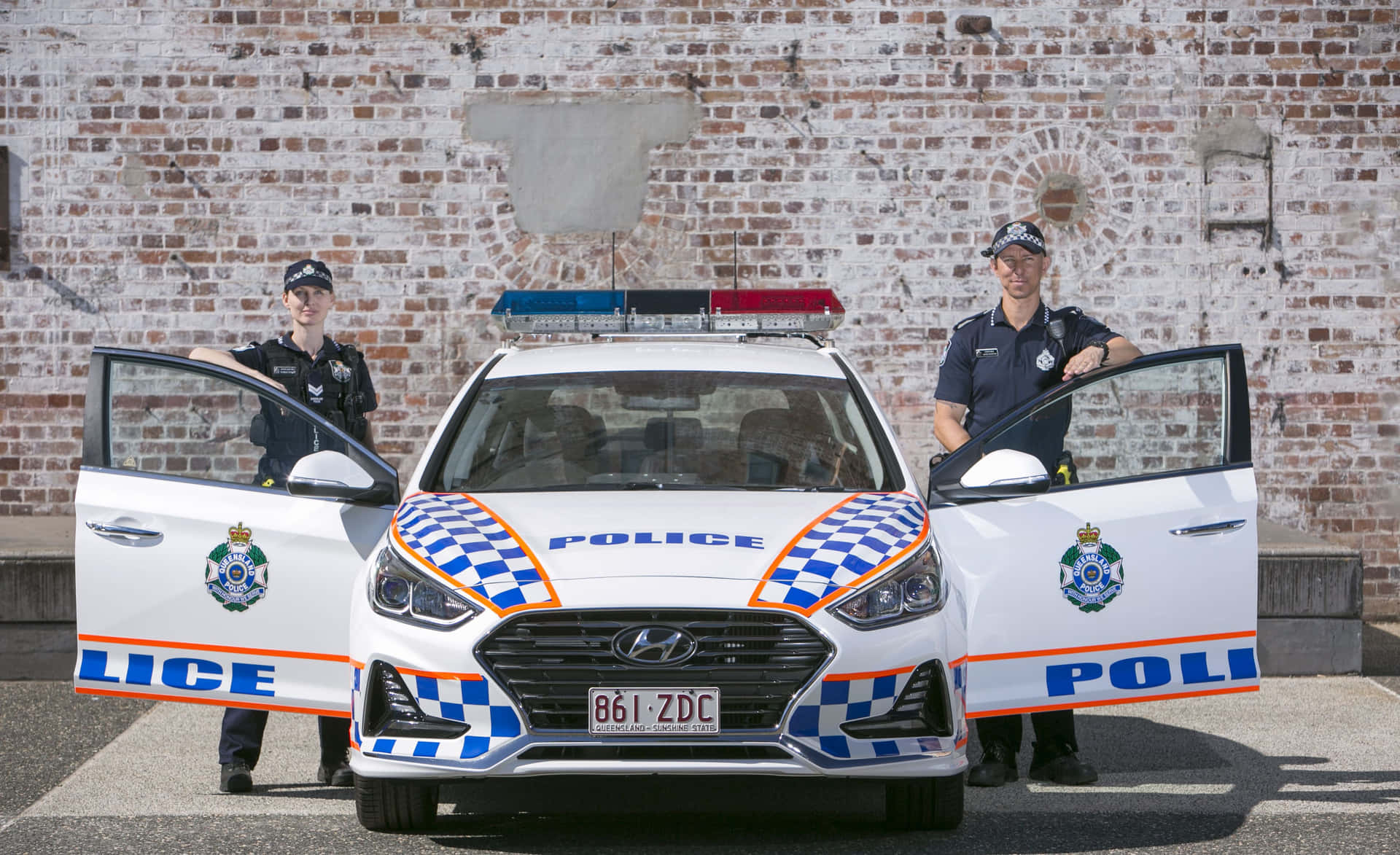 Two Police Officers Standing Next To A Police Car Wallpaper