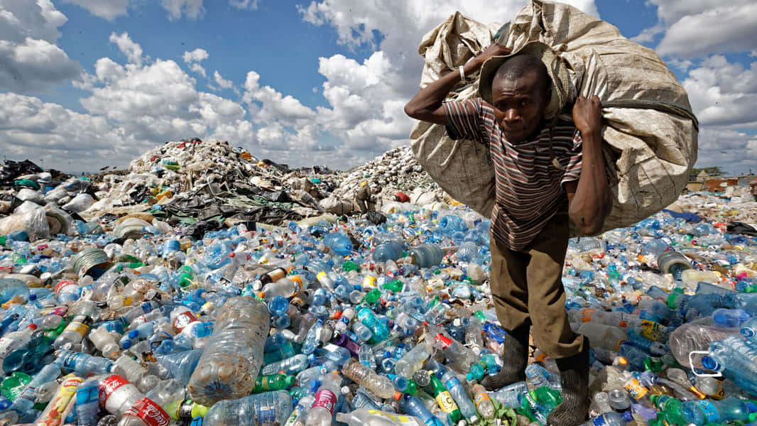 A Man Carrying A Bag Of Plastic Bottles