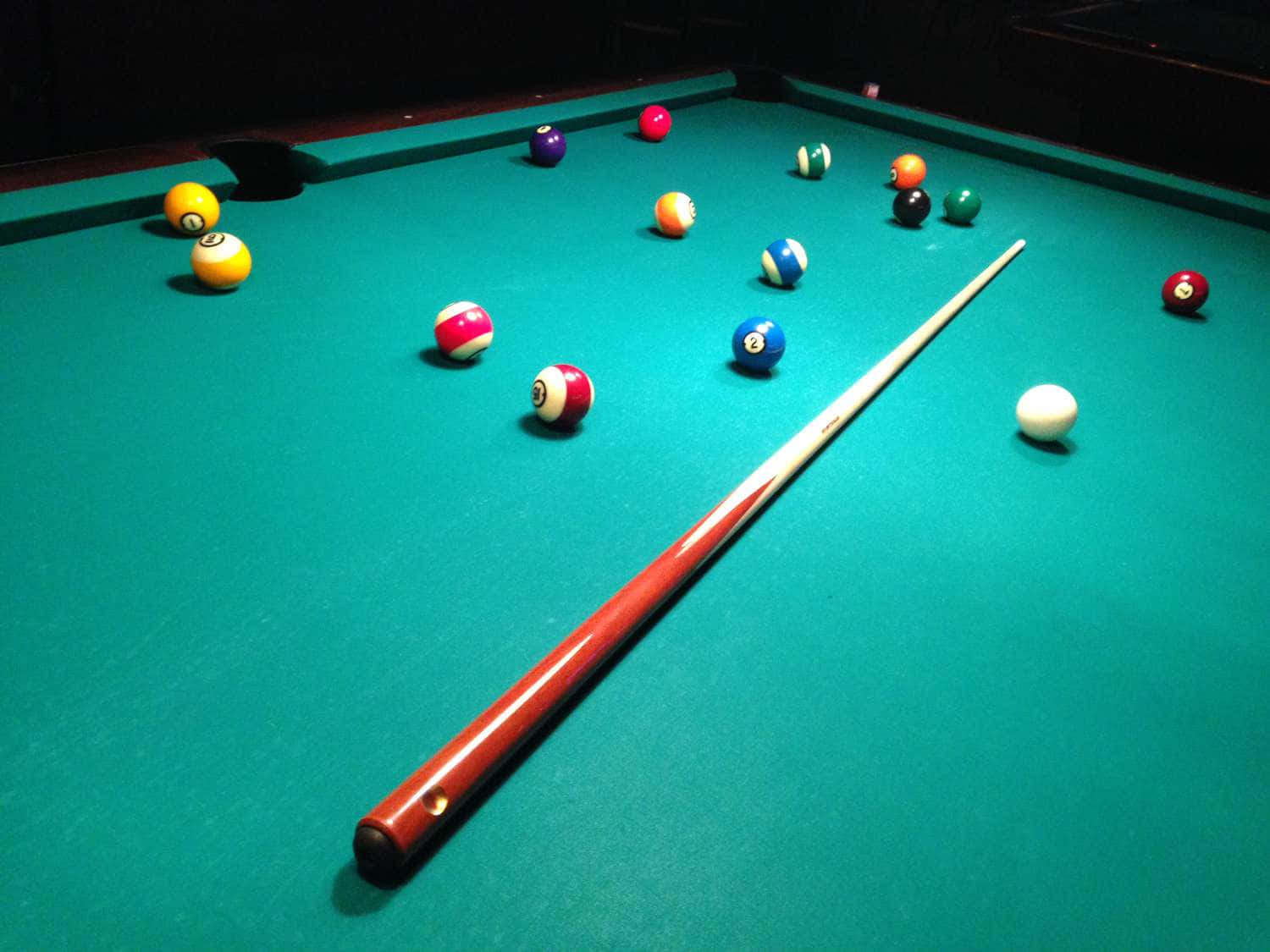A Pool Table With Balls And Cues On It
