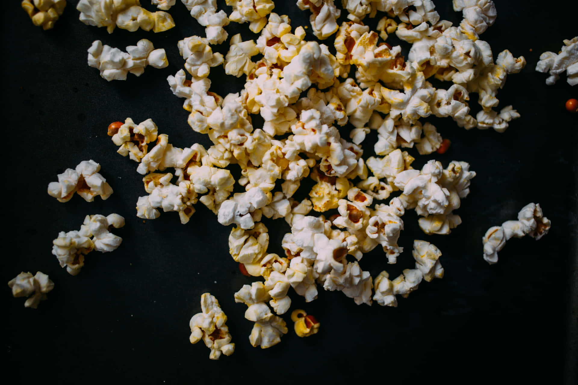 A Pile Of Popcorn On A Black Surface