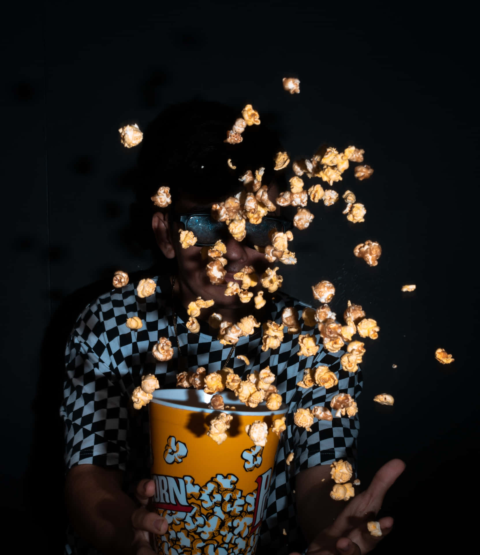A Man Is Throwing Popcorn Into A Bucket