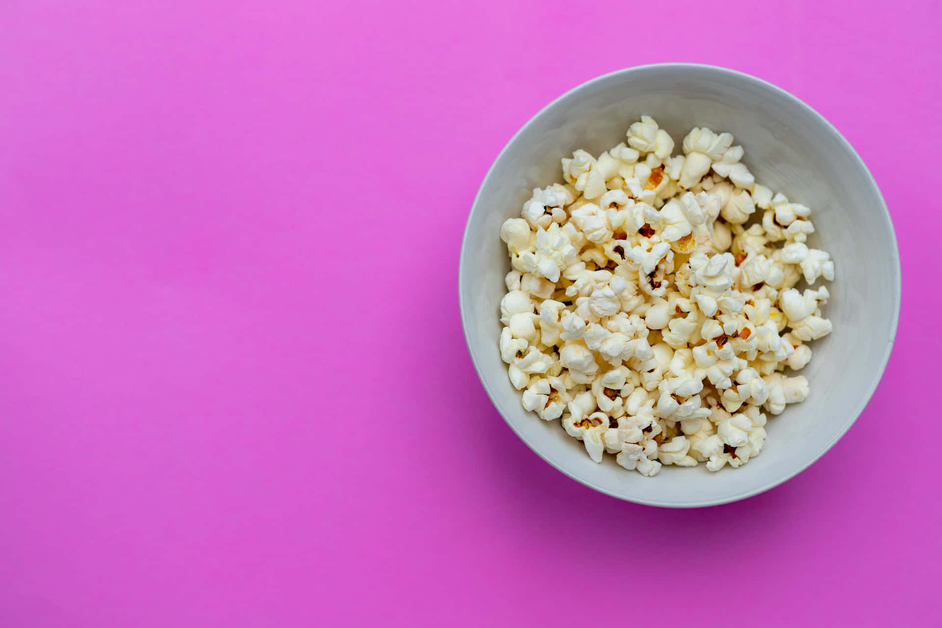 A Bowl Of Popcorn On A Pink Background