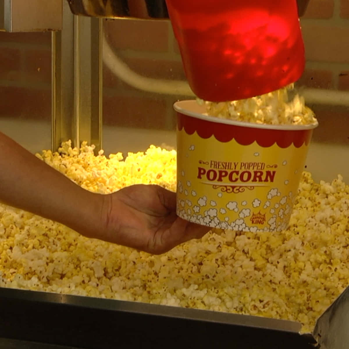 A Person Pouring Popcorn Into A Bucket
