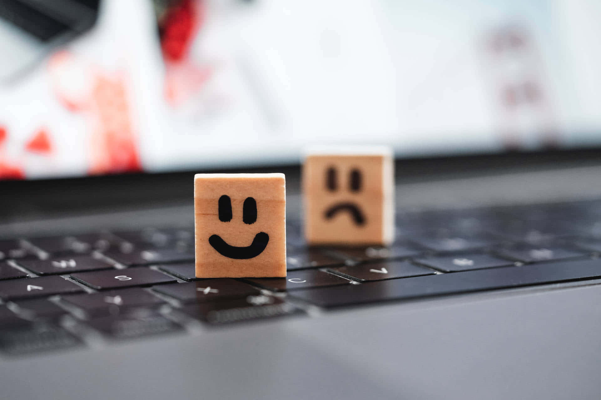Two Wooden Blocks With Smiley Faces On A Laptop Keyboard