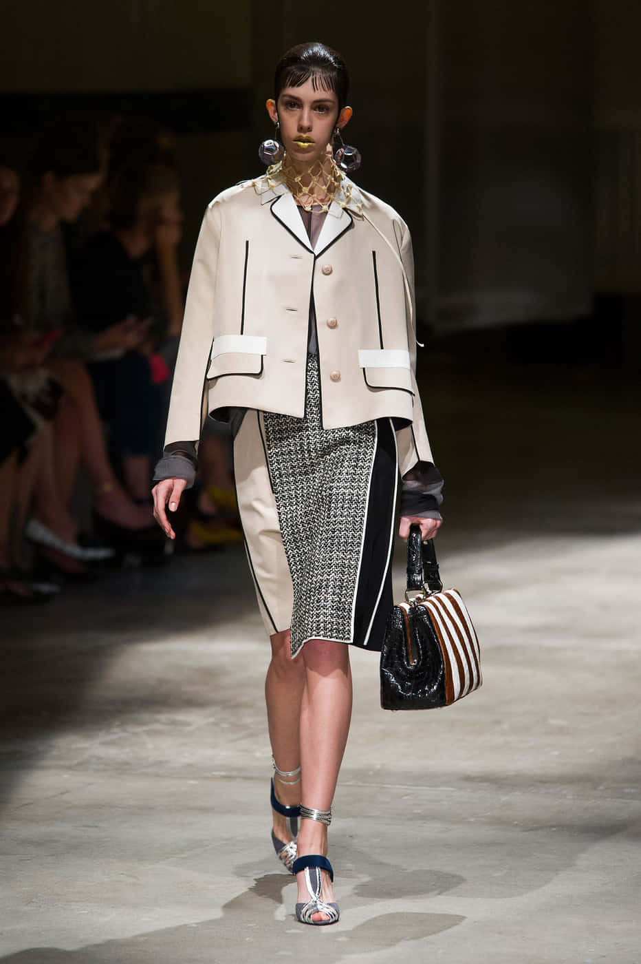 A Woman Walks Down The Runway In A Beige Jacket And Skirt