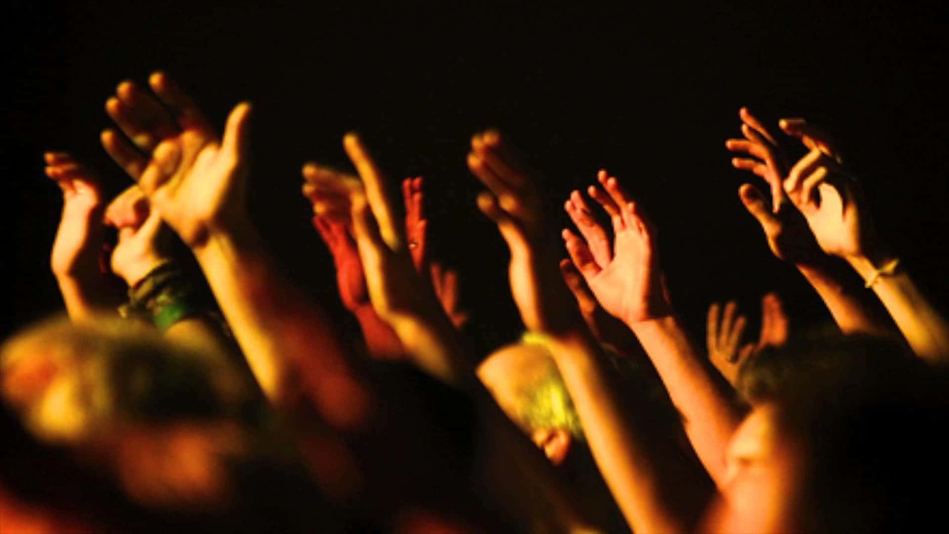 A Crowd Of People Raising Their Hands In The Air