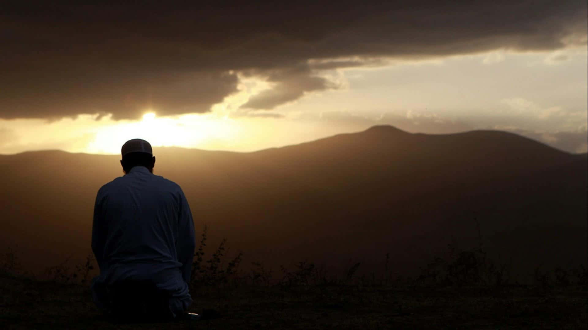 A Man Sitting On A Hill Watching The Sunset