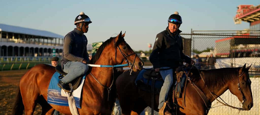 To jockeys, der rider på heste på banen.