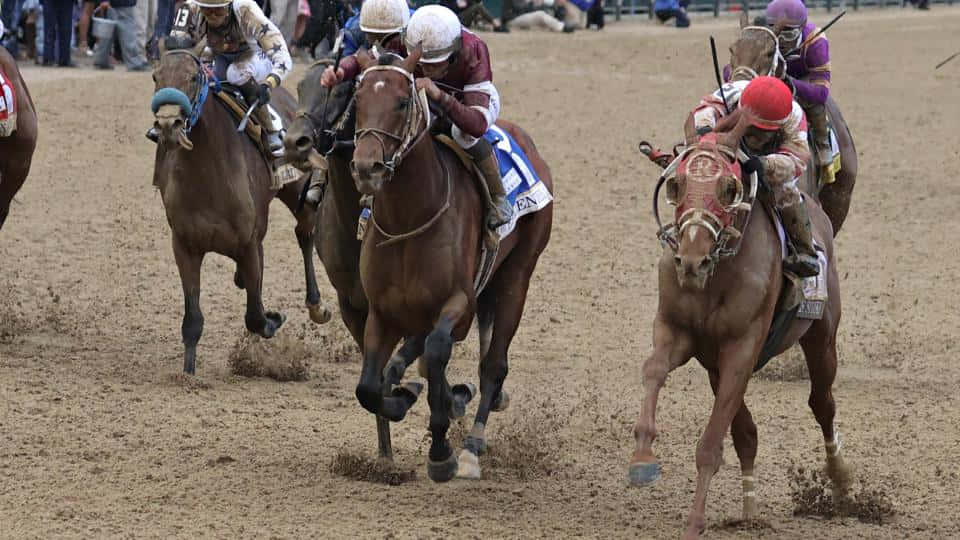 A Group Of Jockeys Are Racing On A Dirt Track
