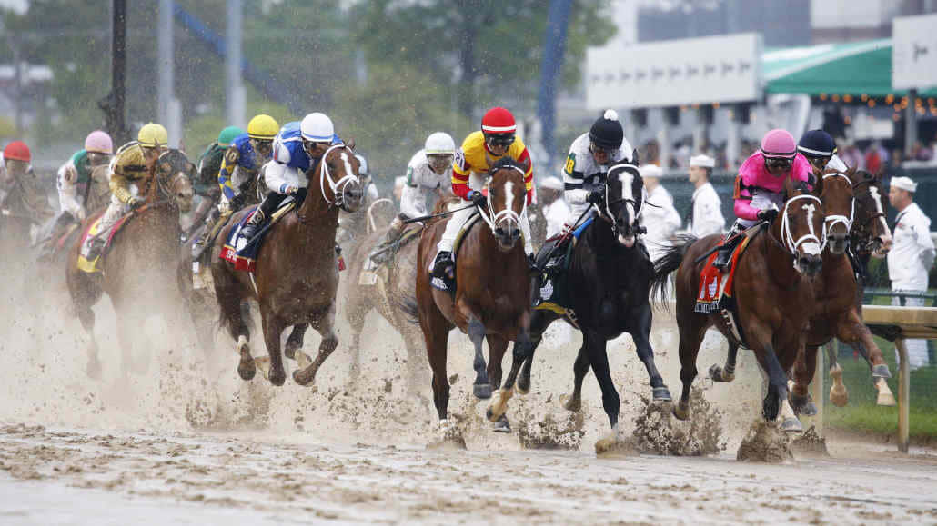 A Group Of Jockeys Racing In A Muddy Race