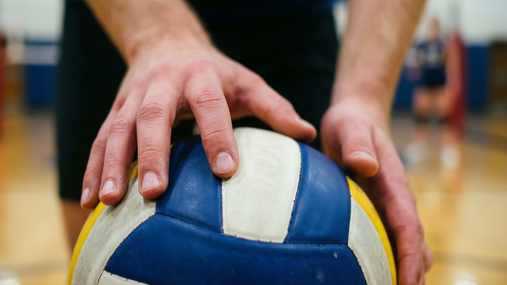 A close-up of hands setting the volleyball with precision.