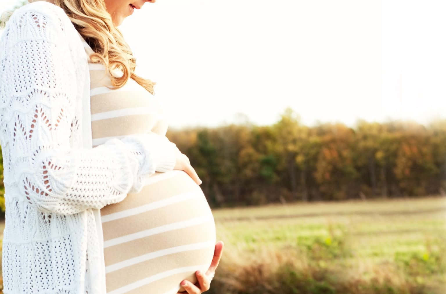 Joyful pregnant woman gazing at ultrasonic scans on a pleasant day.