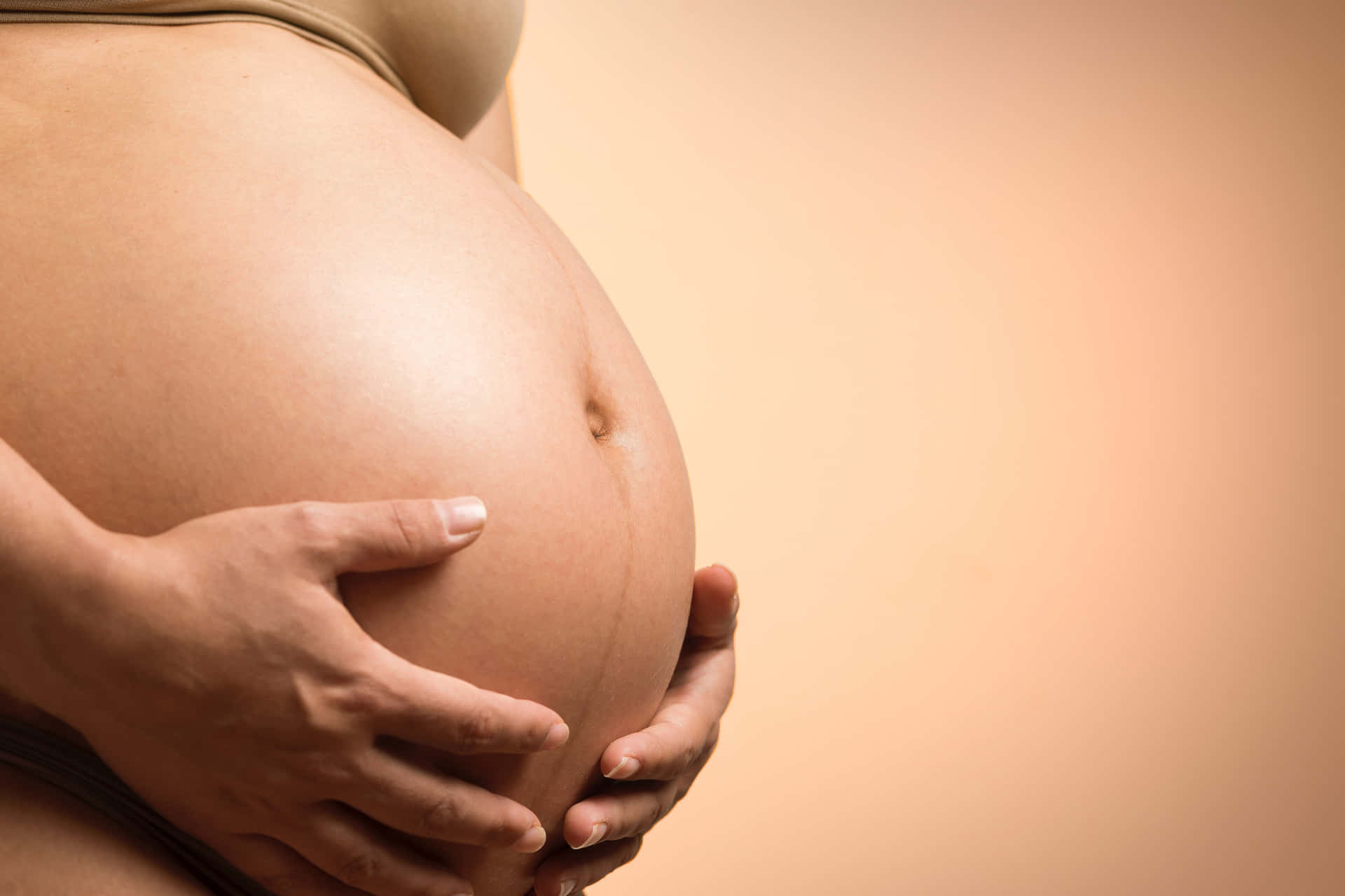 Pregnant woman holding her belly on a wooden bridge