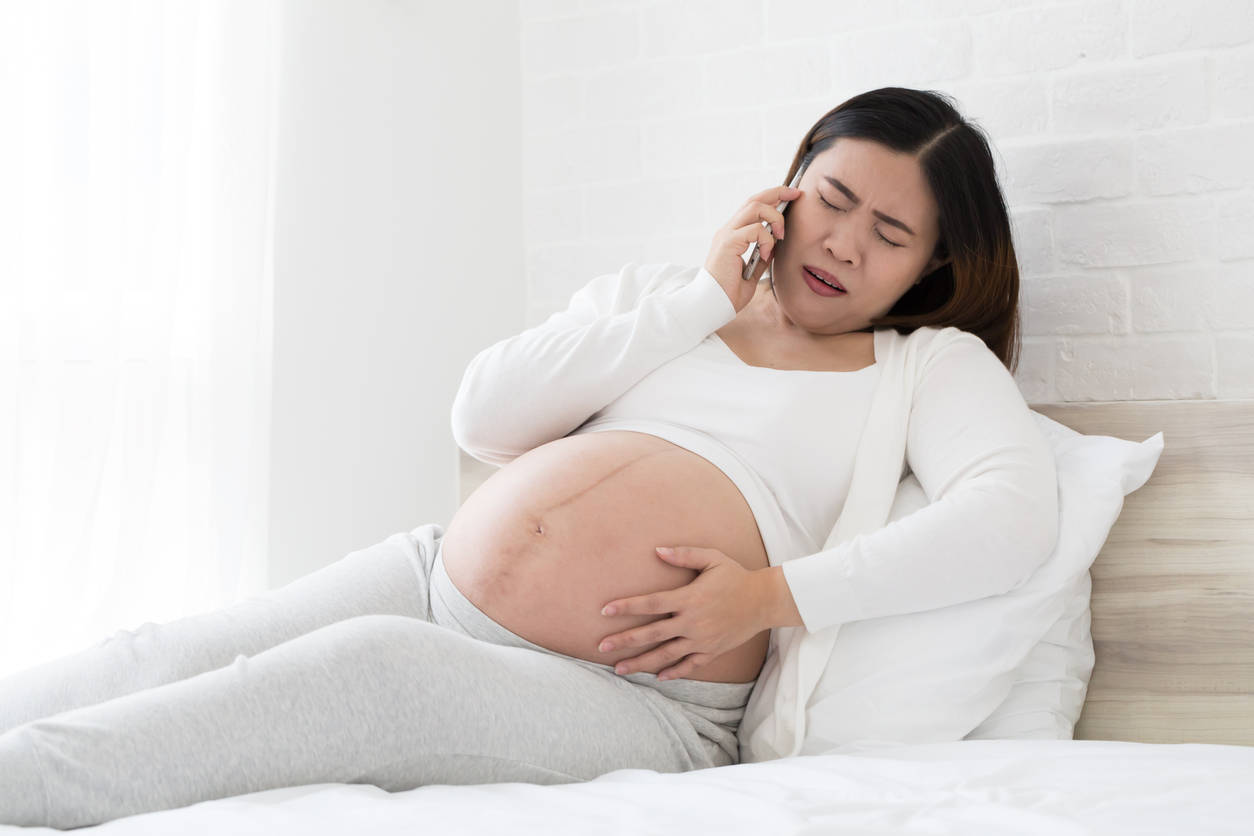 Expectant Mother Experiencing Abdominal Pain During a Phone Call Wallpaper