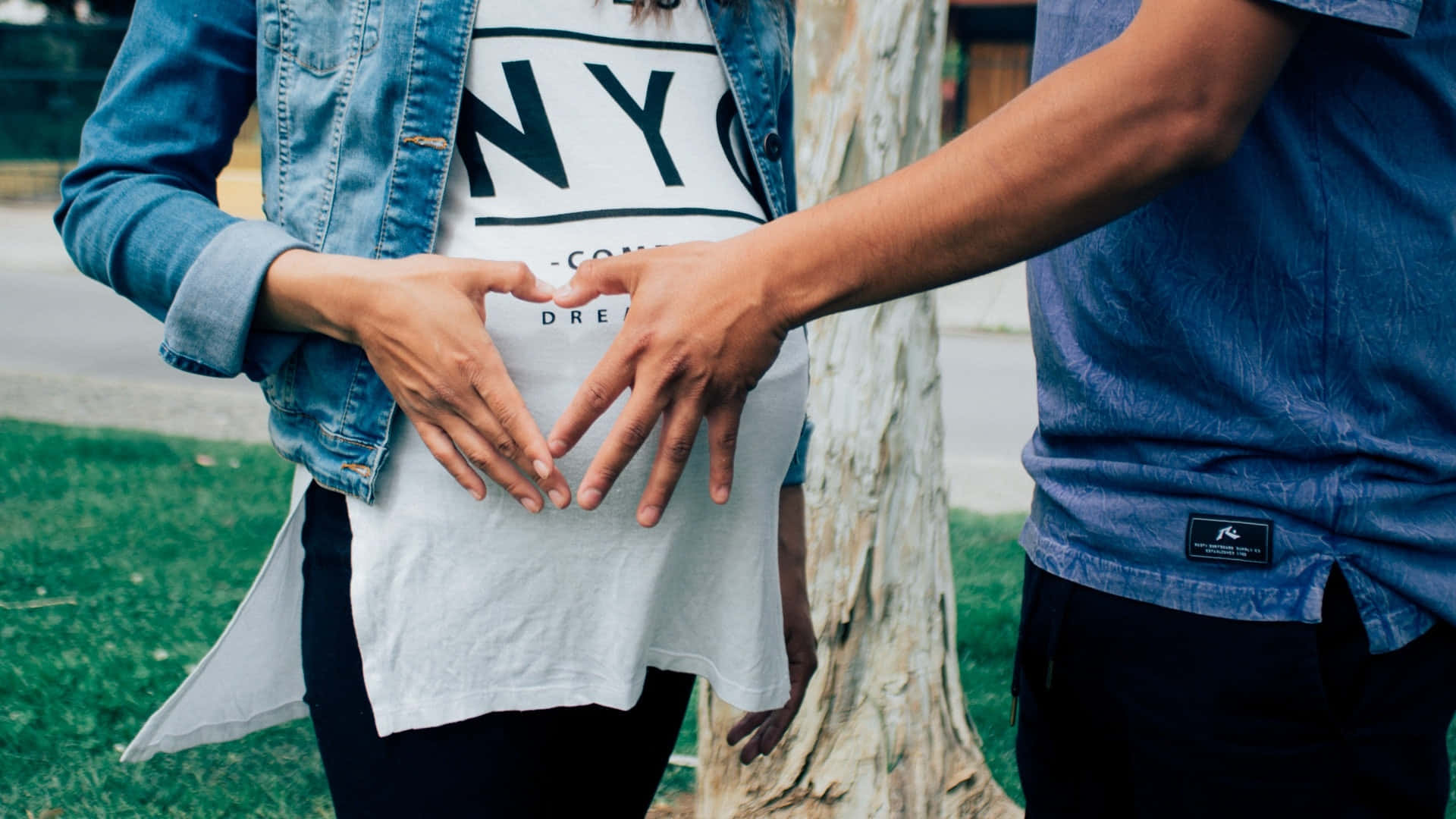 Loving Pregnant Couple Forming Heart With Their Hands Over Baby Bump Wallpaper