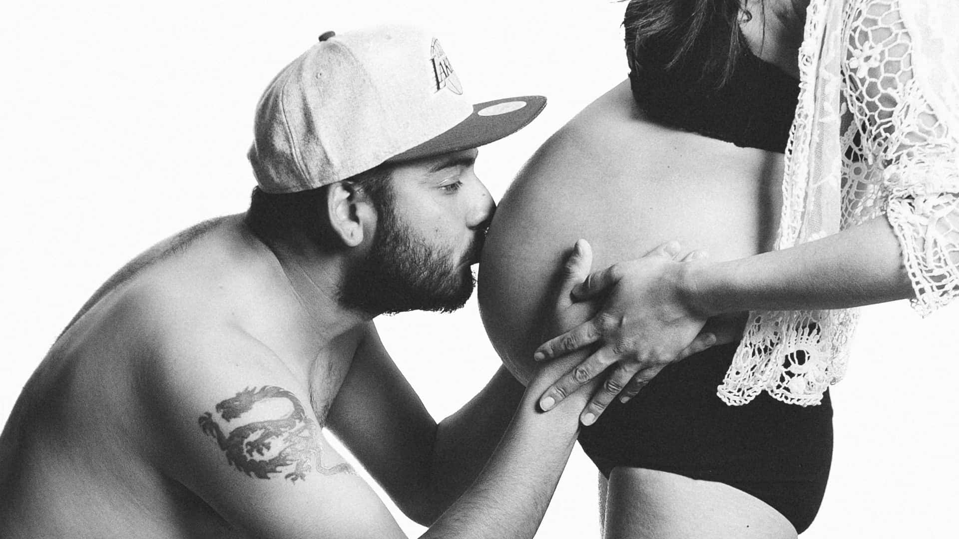 Pregnant Couple Kissing Baby Bump Wallpaper