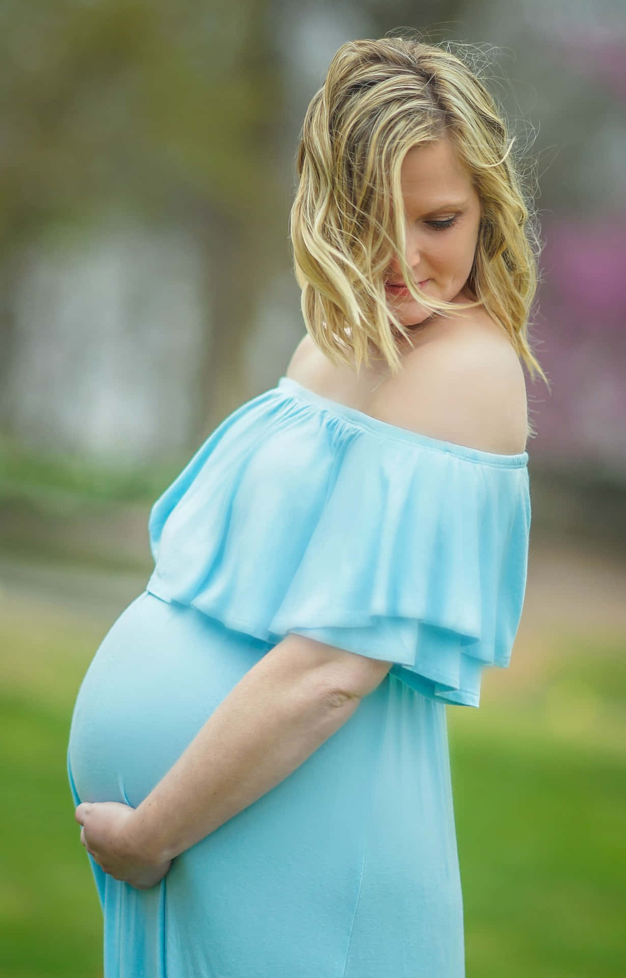 A Pregnant Woman In A Blue Dress Is Posing For A Photo