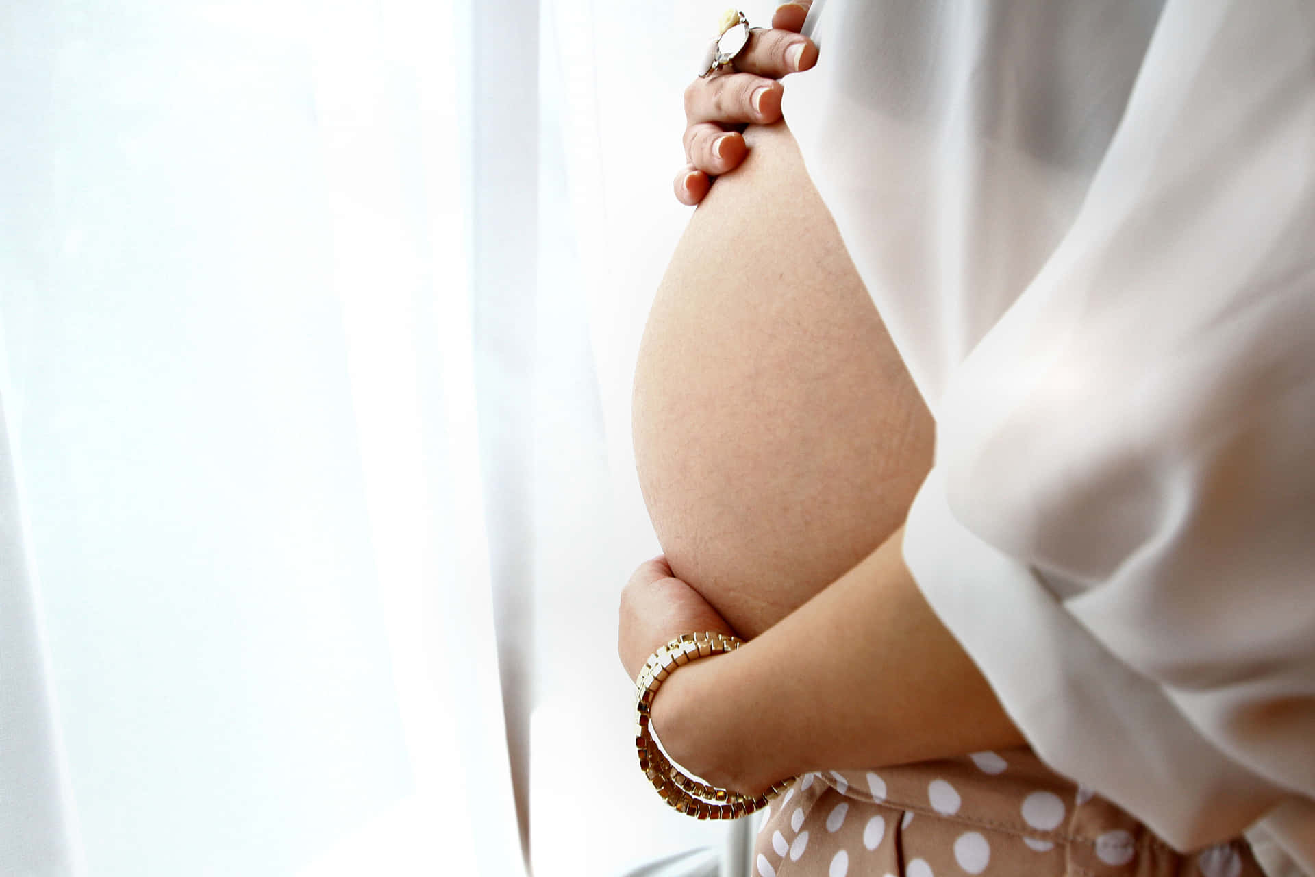 Cherishing Motherhood: Close-up of a Pregnant Woman's Baby Bump Wallpaper