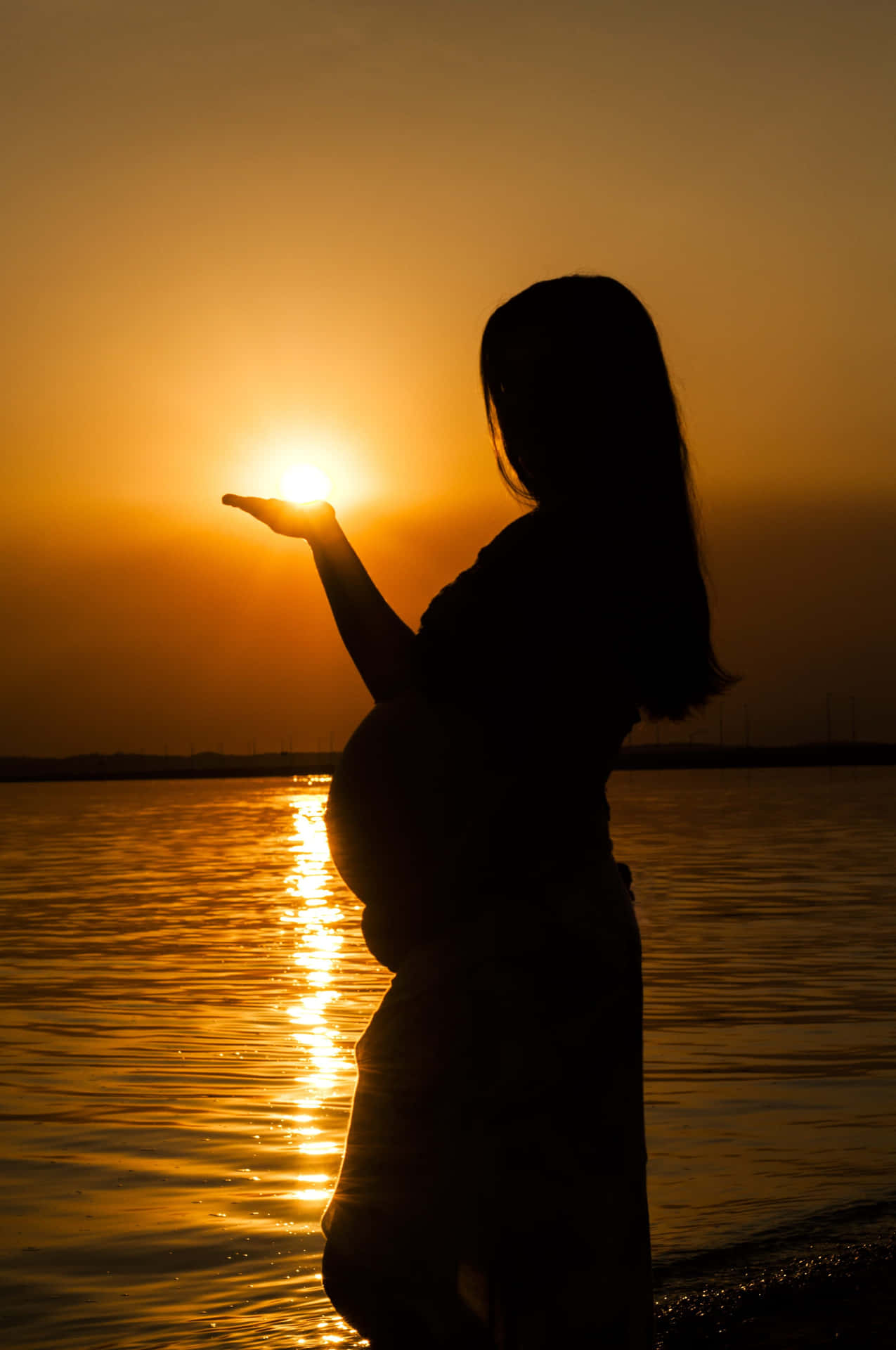Mujerembarazada Sosteniendo El Sol Que Se Pone En La Mano Fondo de pantalla